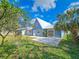 Backyard featuring a stone patio, vibrant green grass, and mature trees under a beautiful blue sky at 950 Sand Crest Dr, Port Orange, FL 32127