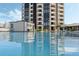 Condo pool with a building reflection on a bright day with lounge chairs and umbrellas nearby at 1 Oceans West Blvd # 6A5, Daytona Beach, FL 32118