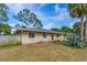 Charming single-story home with a brick facade, red door, and partially fenced yard at 1043 Beulah Dr, Edgewater, FL 32132