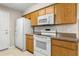 Cozy kitchen featuring white appliances, oak cabinets, tile flooring, and ample storage at 1043 Beulah Dr, Edgewater, FL 32132