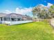 The grass backyard features a screened-in pool area and a wood fence at 1175 Margina Ave, Daytona Beach, FL 32114