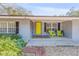 Inviting front entrance with a bright yellow door and chairs, complemented by lovely landscaping at 128 Dixwood Ave, Edgewater, FL 32132