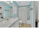 Bright teal bathroom boasts a bathtub and shower combination and ample counter space with modern finishes at 1462 General Mcarthur Ave, Daytona Beach, FL 32124