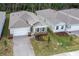 Drone view of a community home with a two-car garage, charming shutters, brick accents, and lush backyard at 1731 Red Rock Rd, New Smyrna Beach, FL 32168