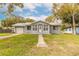 Cozy single-story home with a manicured lawn, mature trees, metal roof and an inviting front entrance at 254 Tanner St, New Smyrna Beach, FL 32168