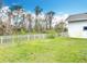 Large grassy backyard with tall trees and white fence at 2590 Erena Dr, New Smyrna Beach, FL 32168