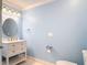 Powder blue bathroom with a white vanity and a modern round mirror and lighting fixture at 2590 Erena Dr, New Smyrna Beach, FL 32168