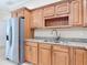 Well-lit kitchen featuring stainless steel refrigerator, wood cabinets, granite counters, and undermount sink at 2590 Erena Dr, New Smyrna Beach, FL 32168