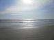 Calm beach scene featuring gentle waves meeting the shore, set against a tranquil horizon, showcasing a serene coastal escape at 26 Birdie Dr, New Smyrna Beach, FL 32168