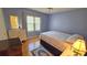 A cozy bedroom featuring light blue walls, wood flooring, and natural light from the window at 26 Birdie Dr, New Smyrna Beach, FL 32168