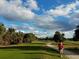 Scenic golf course with lush green grass, palm trees, and a walking path at 26 Birdie Dr, New Smyrna Beach, FL 32168