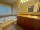 Bathroom featuring a soaking tub, toilet, and vanity with brown cabinets at 2669 Sicily Dr, New Smyrna Beach, FL 32168