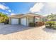 Home exterior view featuring a three car garage with a brick paved drive and mature landscaping at 2921 Linari Ct, New Smyrna Beach, FL 32168