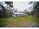 Back exterior of home with metal roof, deck, and surrounding trees at 2995 Ragis Rd, Edgewater, FL 32132