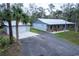 Single story home with a metal roof and an adjacent garage with large driveway at 2995 Ragis Rd, Edgewater, FL 32132