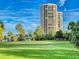 Scenic view of the golf course with green grass, palm trees, and high-rise buildings in the background at 3 Oceans West Boulevard # 3B1, Daytona Beach Shores, FL 32118