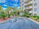 Exterior view of a parking area near tropical trees, landscaping, and a residential tower at 3 Oceans West Boulevard # 3B, Daytona Beach Shores, FL 32118