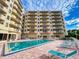 Exterior shot of a condo building pool with lounge chairs and views of private balconies at 3 Oceans West Boulevard # 3B, Daytona Beach Shores, FL 32118