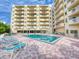 Resort-style pool with brick patio and lounge chairs by a condo building with multiple balconies at 3 Oceans West Boulevard # 3B, Daytona Beach Shores, FL 32118