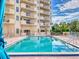 Exterior view of a pool with lounge chairs and condos with balconies overlooking the water at 3 Oceans West Boulevard # 3B, Daytona Beach Shores, FL 32118