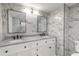 Modern bathroom with double vanity, granite countertop, and elegant marble tile walls at 3001 S Atlantic Ave # 204, New Smyrna Beach, FL 32169