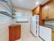 Corner view of the kitchen features granite countertops, wooden cabinets, tile floors, and white appliances at 315 N Causeway # 405, New Smyrna Beach, FL 32169