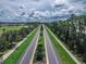 Scenic aerial view of a long, straight road lined with lush trees and landscaping within a residential community at 3368 Tuscano Ne Ave, New Smyrna Beach, FL 32168