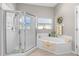 The bright bathroom features a glass enclosed shower and a soaking tub with white tile at 3783 Sweet Grove Ct, Port Orange, FL 32129