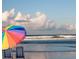 Relaxing beach view with beach chairs under a rainbow umbrella and gentle waves at 45 Sandra Cir, New Smyrna Beach, FL 32168