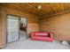 Covered outdoor patio with wood ceiling, featuring a cozy red couch for relaxation and a sliding glass door to the home at 456 Shorewood Ln, New Smyrna Beach, FL 32168