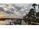 Picturesque sunset view along a wooden dock lined with palm trees and waterfront properties at 47 Jacaranda Cay Ct # 470, New Smyrna Beach, FL 32169