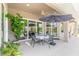 Covered patio with dining set and umbrella overlooking a beautiful backyard and reflected sliding glass doors at 512 Romdini St, New Smyrna Beach, FL 32168