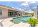 Aerial view of a sparkling screened-in pool area surrounded by lush landscaping and blue skies at 512 Romdini St, New Smyrna Beach, FL 32168