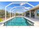 Aerial view of a sparkling screened-in pool area surrounded by lush landscaping and blue skies at 512 Romdini St, New Smyrna Beach, FL 32168