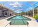 Inviting screened-in pool with a seating area and clear blue skies reflecting in the water at 512 Romdini St, New Smyrna Beach, FL 32168