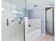 Clean bathroom features a glass enclosed shower and soaking tub combo with white tile and marble floors at 5300 S Atlantic Ave # 5-407, New Smyrna Beach, FL 32169