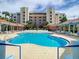 Community pool with surrounding lounge chairs and palm trees with the building's exterior in the background at 5300 S Atlantic Ave # 5-407, New Smyrna Beach, FL 32169