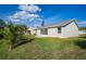 View of the home's backyard with a green lawn, and mature landscaping at 5431 Landis Ave, Port Orange, FL 32127