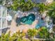 Aerial view of a backyard oasis with a freeform pool, lush landscaping, and an outdoor dining area at 604 S Atlantic Ave, New Smyrna Beach, FL 32169