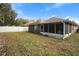 Exterior view of backyard with grass, trees, and a screened-in porch attached to the back of house at 634 Coral Trace Blvd, Edgewater, FL 32132