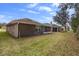 Exterior view of backyard with grass, trees, and a screened-in porch attached to the back of house at 634 Coral Trace Blvd, Edgewater, FL 32132