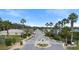 Inviting community entrance with lush landscaping, decorative gate and palm trees lining the street at 634 Coral Trace Blvd, Edgewater, FL 32132