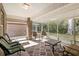The sunroom includes a patterned rug, multiple seating options, and views of the trees outside at 634 Coral Trace Blvd, Edgewater, FL 32132