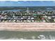 Aerial view of a coastal neighborhood, with homes lined along a sandy beach against a blue sky with white clouds at 6443 Engram Rd, New Smyrna Beach, FL 32169