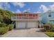 Two-story home showcasing a salmon exterior, two-car garage and white railing under a blue sky with white clouds at 6443 Engram Rd, New Smyrna Beach, FL 32169