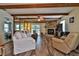 Spacious living room features a stone fireplace, wood beams, fan, neutral tones, and sliding glass doors at 6443 Engram Rd, New Smyrna Beach, FL 32169