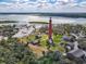 Aerial view of a lighthouse surrounded by smaller homes and buildings with blue water and blue skies at 86 Rains Ct, Ponce Inlet, FL 32127