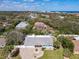 An aerial view of a light blue home with palm trees, a brick driveway and screened-in pool in the distance at 86 Rains Ct, Ponce Inlet, FL 32127