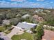 An aerial view of a light blue home with lush landscaping, a brick driveway and a glimpse of a screened-in pool in the back at 86 Rains Ct, Ponce Inlet, FL 32127