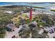 A high aerial view of a lighthouse surrounded by several houses with a parking lot and water in the distance at 86 Rains Ct, Ponce Inlet, FL 32127